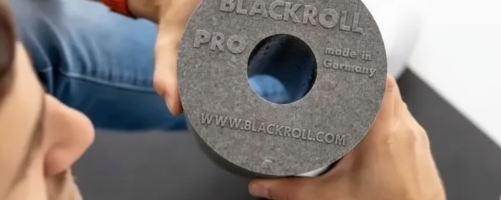 Persona sosteniendo el rodillo Blackroll Pro en primer plano, mostrando el logo grabado