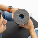 Persona sosteniendo el rodillo Blackroll Pro en primer plano, mostrando el logo grabado