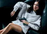 Mujer usando una pistola de masaje Hyperice sentada en un sillón