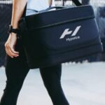 Mujer caminando al aire libre cargando la maleta Hyperice Normatec por su asa