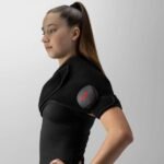 Mujer joven usando un Venom 2 Shoulder de Hyperice en el hombro