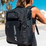 Mujer usando la mochila Hyperice para Normatec en exterior