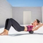 Mujer usando el Duoball para masajear la zona lumbar en posición de puente