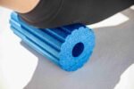 Detalle de Blackroll Groove Pro azul en uso bajo la pierna, superficie con surcos visible