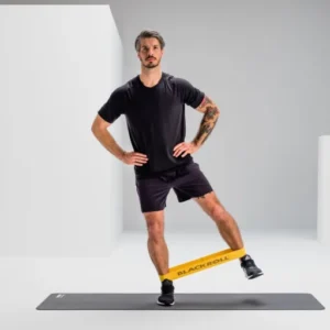 Hombre haciendo paso lateral con Blackroll Loop Band alrededor de los tobillos
