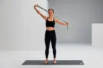 Mujer usando Blackroll Stretch Band verde para apertura de hombro y pecho, brazos en alto
