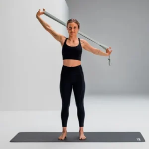 Mujer usando Blackroll Stretch Band verde para apertura de hombro y pecho, brazos en alto