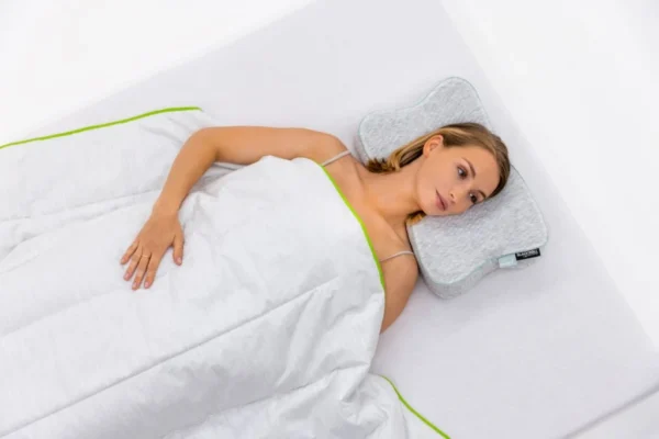 Vista cenital de mujer bajo la manta, apoyada sobre la almohada con funda Allergoprotect