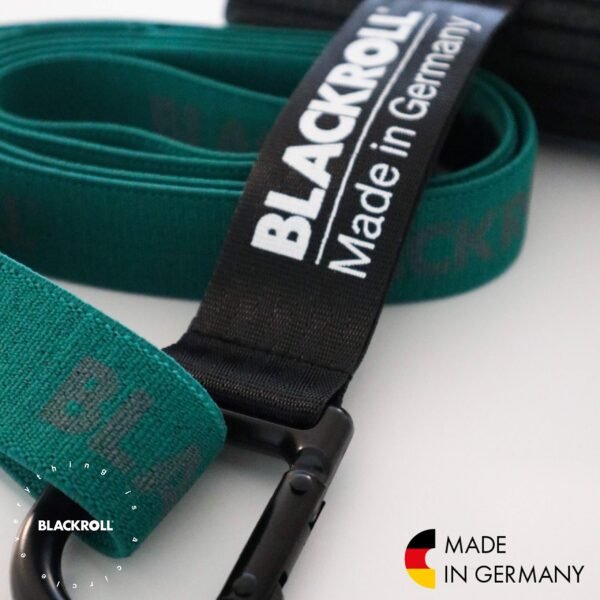 Detalle en primer plano del mosquetón negro del Blackroll Hook sujeto a una banda elástica verde con el texto BLACKROLL Made in Germany