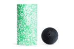 Rodillo Med verde/blanco de Blackroll junto a la Ball 12 negra, vista frontal sobre fondo blanco