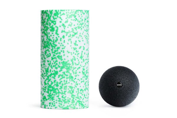 Rodillo Med verde/blanco de Blackroll junto a la Ball 12 negra, vista frontal sobre fondo blanco