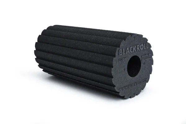 Foam roller Blackroll Flow negro con superficie de bordes bidireccional, vista en ángulo sobre fondo blanco