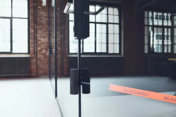 Interior de un estudio con equipamiento de entrenamiento y una banda elástica naranja de Blackroll en el piso, ambientación de gimnasio