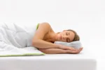 Mujer durmiendo de lado sobre almohada con funda Allergoprotect y ribete verde