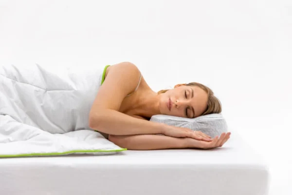 Mujer durmiendo de lado sobre almohada con funda Allergoprotect y ribete verde