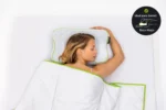 Mujer durmiendo boca arriba sobre la Blackroll Recovery Pillow, con insignia de postura recomendada