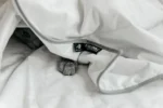 Detalle de la esquina de la Blackroll Recovery Blanket Summer mostrando la etiqueta de marca y el ojal metálico