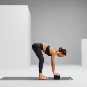 Mujer en postura de flexión hacia adelante con las manos apoyadas sobre el Block, sobre mat de yoga