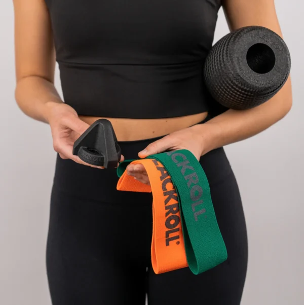 Mujer sosteniendo el Trigger negro y las Loop Band naranja y verde, con el rodillo Twin bajo el brazo
