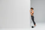 Mujer haciendo elevación de talón apoyada contra la pared con el Blackroll Block bajo el pie