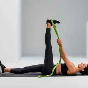 Mujer acostada boca arriba usando la Multi-Band verde para estirar la pierna extendida hacia arriba