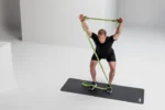 Hombre en semi-sentadilla sosteniendo la Multi-Band verde anclada bajo los pies, brazos elevados hacia el pecho