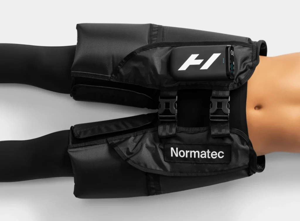 Vista cercana del Normatec Elite Cadera puesto en la cintura de una persona, mostrando las hebillas de ajuste, el logo Hyperice en la unidad de control y el texto Normatec en la banda frontal