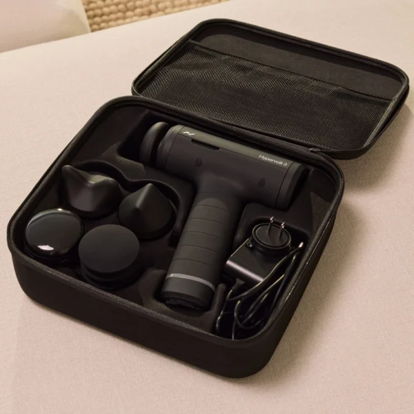 Hypervolt 3 con sus 5 cabezales intercambiables, cargador y estuche de transporte abierto